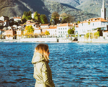 Side view of woman standing by river in city