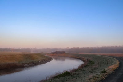 Scenic view of land against clear sky during sunset