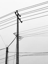 Low angle view of electricity pylon against clear sky