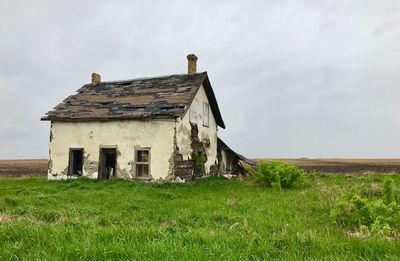 Abandoned house on field against sky