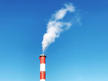 Low angle view of smoke stacks against blue sky