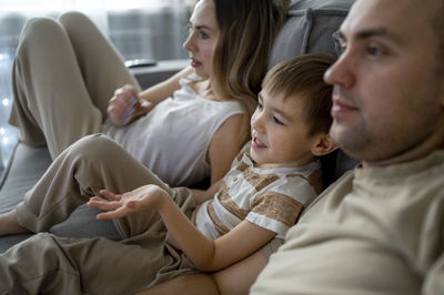 Mother and father with son watching tv at home