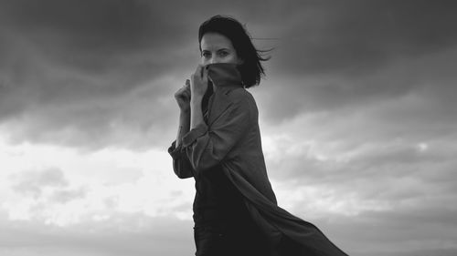 Low angle view of woman standing against sky during sunset