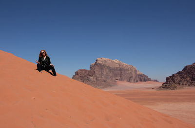 Man skiing on desert against clear sky