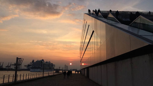 Silhouette of people at harbor during sunset