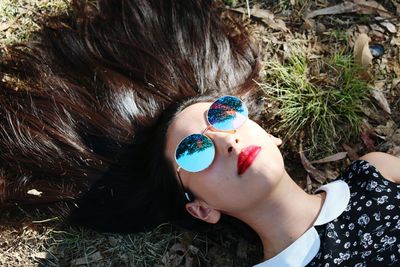 High angle view of young woman wearing sunglasses with fanned out hair on ground