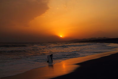 Scenic view of beach against orange sky