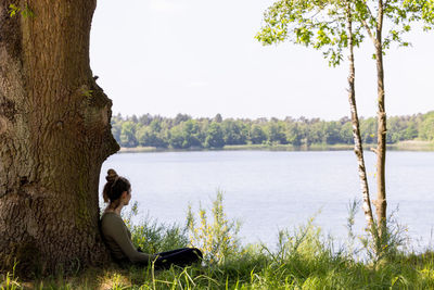 Rear view of woman sitting by lake