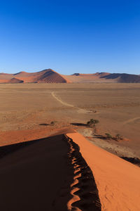 Scenic view of desert against clear blue sky