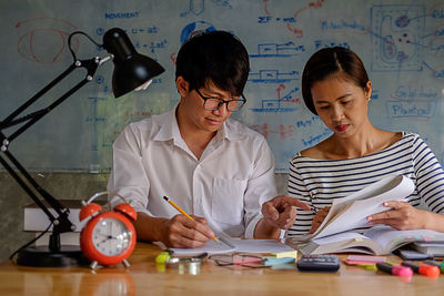 Friends studying with school supplies on table at home