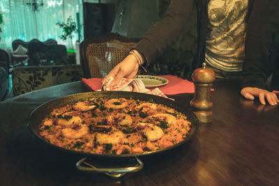 Midsection of woman serving food on table