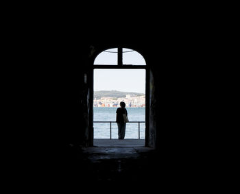 Rear view of woman standing by railing against river