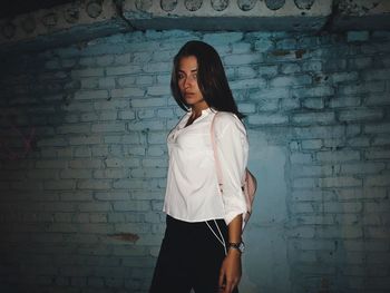 Full length of young woman standing against brick wall