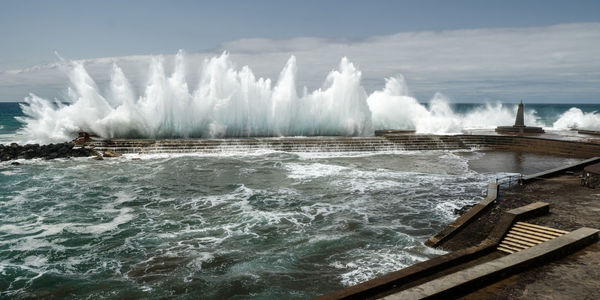 Panoramic view of sea waves splashing against sky