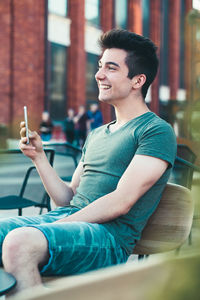 Young man looking away while sitting on mobile phone