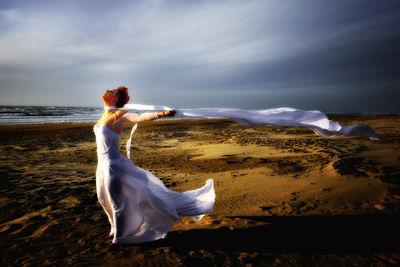 Woman standing on beach against sky