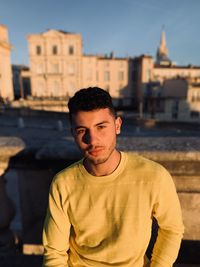 Portrait of young man standing against city