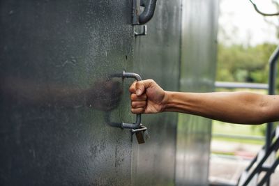 Cropped hands holding metal handle of door