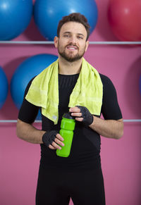 Portrait of man holding camera while standing against wall