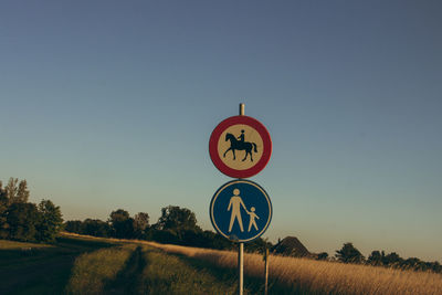 Road sign on field against clear sky