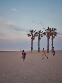 People at beach against sky during sunset