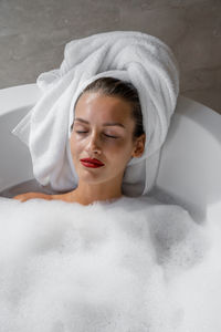 Portrait of woman wearing red lipstick relaxing in bath