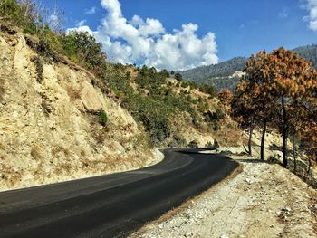 Road amidst trees against sky