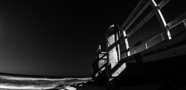 Illuminated building by sea against clear sky at night
