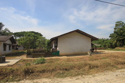 House on field by building against sky