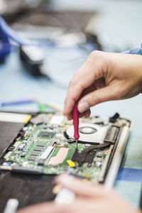 Cropped hand of technician repairing computer part on table