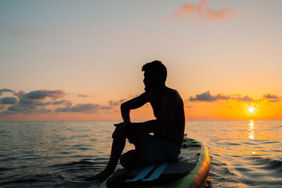 A man is sailing on a sup board at sunset on the sea. high quality photo