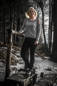 Portrait of woman standing by tree in forest