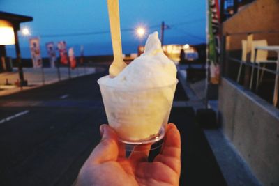 Close-up of hand holding ice cream cone at night