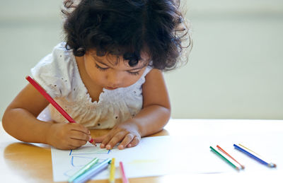 High angle view of girl drawing on book at table