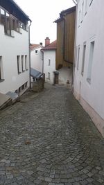 Cobblestone street amidst buildings against sky