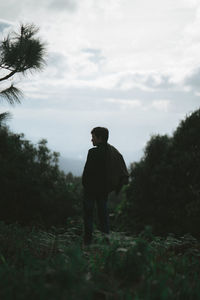 Man standing in forest against sky