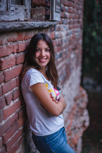 Portrait of smiling woman standing against brick wall