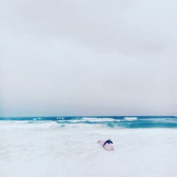 Surfers with surfboards in sea against sky