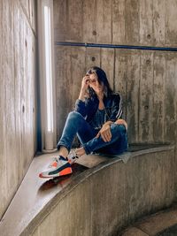 Full length of woman sitting against wall