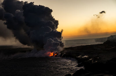 High angle view of lava flowing into sea at big island during sunset
