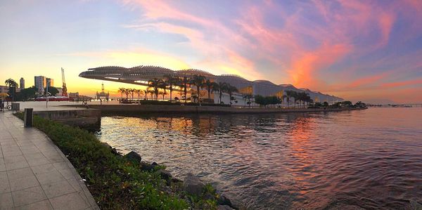 Scenic view of sea by buildings against sky during sunset