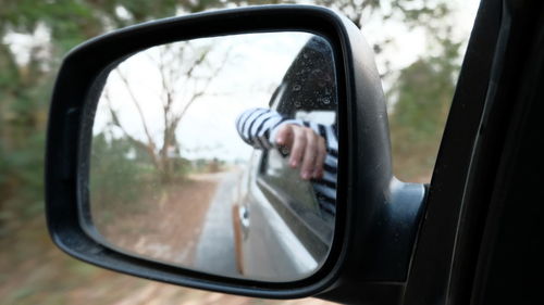 Reflection of man on side-view mirror