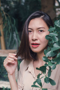 Portrait of young woman holding plant