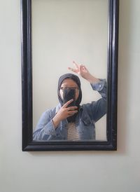 Portrait of woman photographing through window