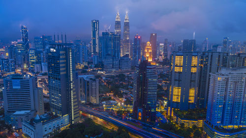 Illuminated buildings in city against sky