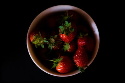 High angle view of strawberries in bowl against black background