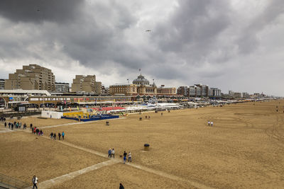 People on beach by buildings against sky