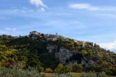 Low angle view of rocks and trees against sky