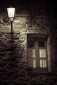 Low angle view of illuminated lamp on wall of old building