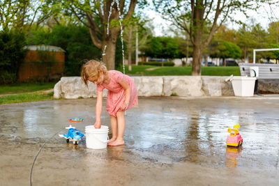 Little girl playing with toys at splash pad playground . child at water park with fountain